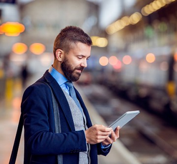 Man looking at electronic device at train station
